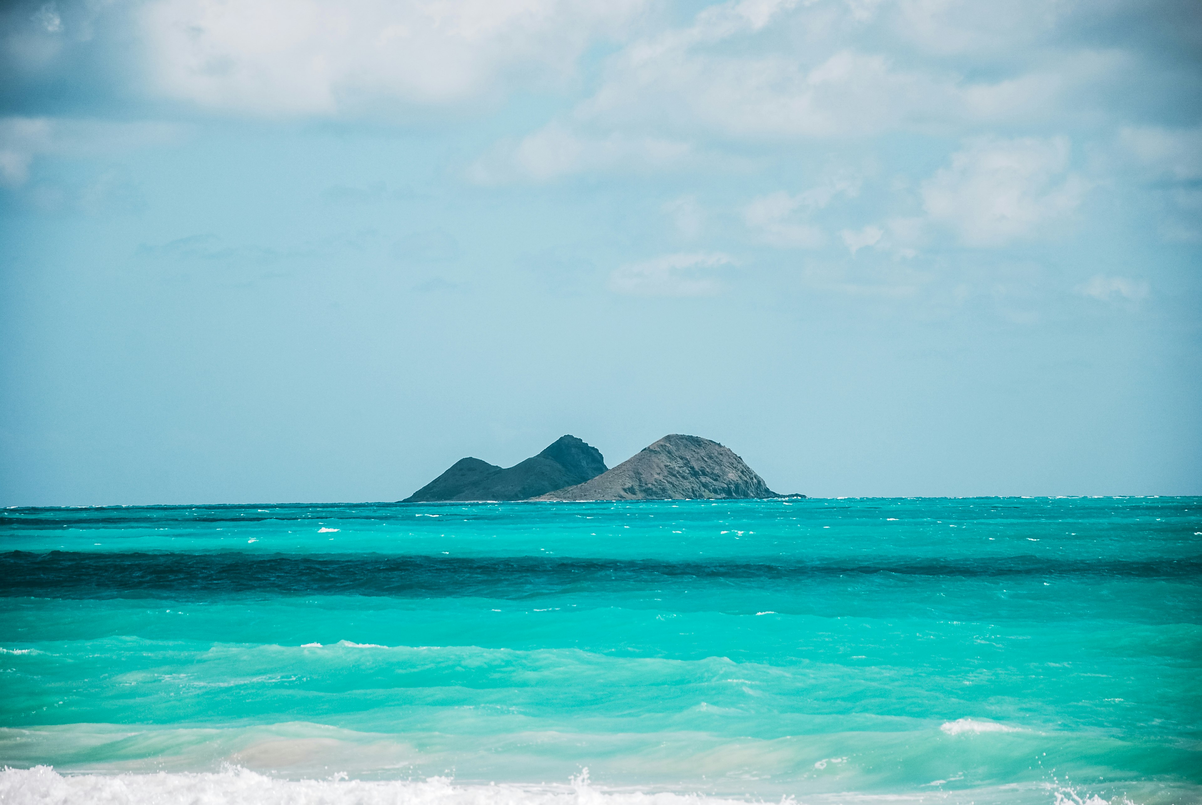 green and brown mountain beside body of water under white clouds during daytime